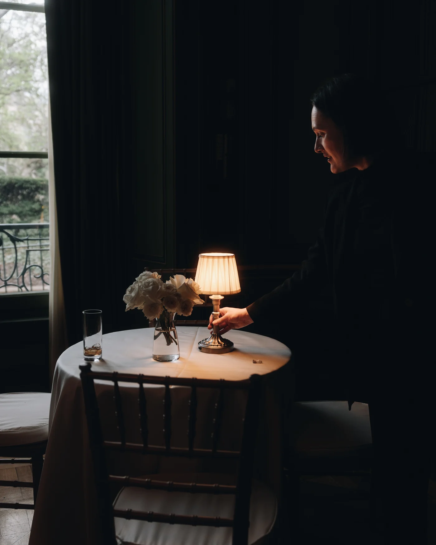 A single lamp and a low arrangement of flowers on a side table