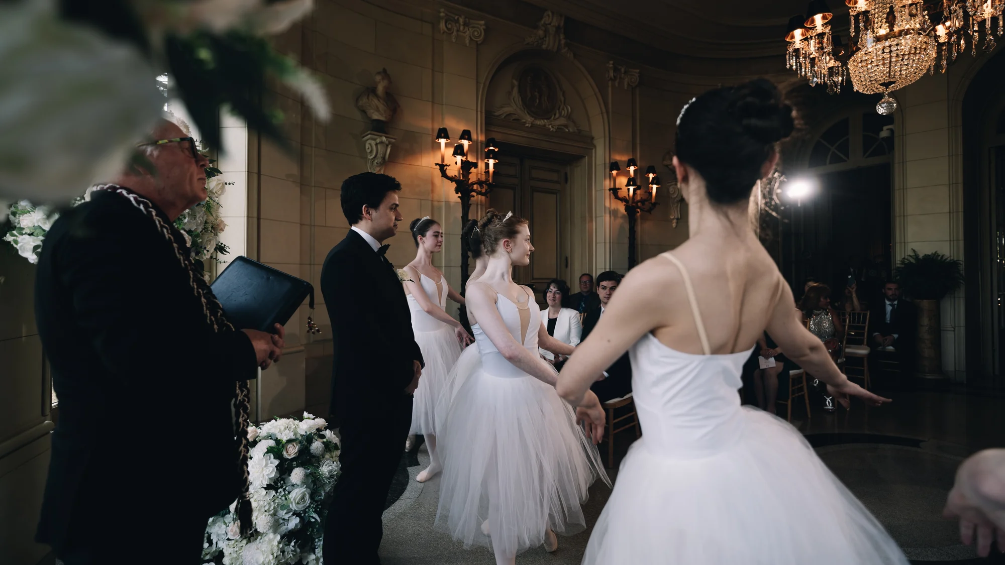 Ballerinas in white performing during the ceremony in front of the seated guests