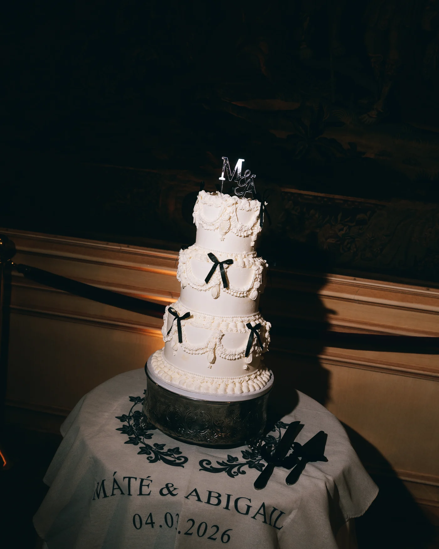 The tiered white cake tied with black bows, both their names and the date painted across the front