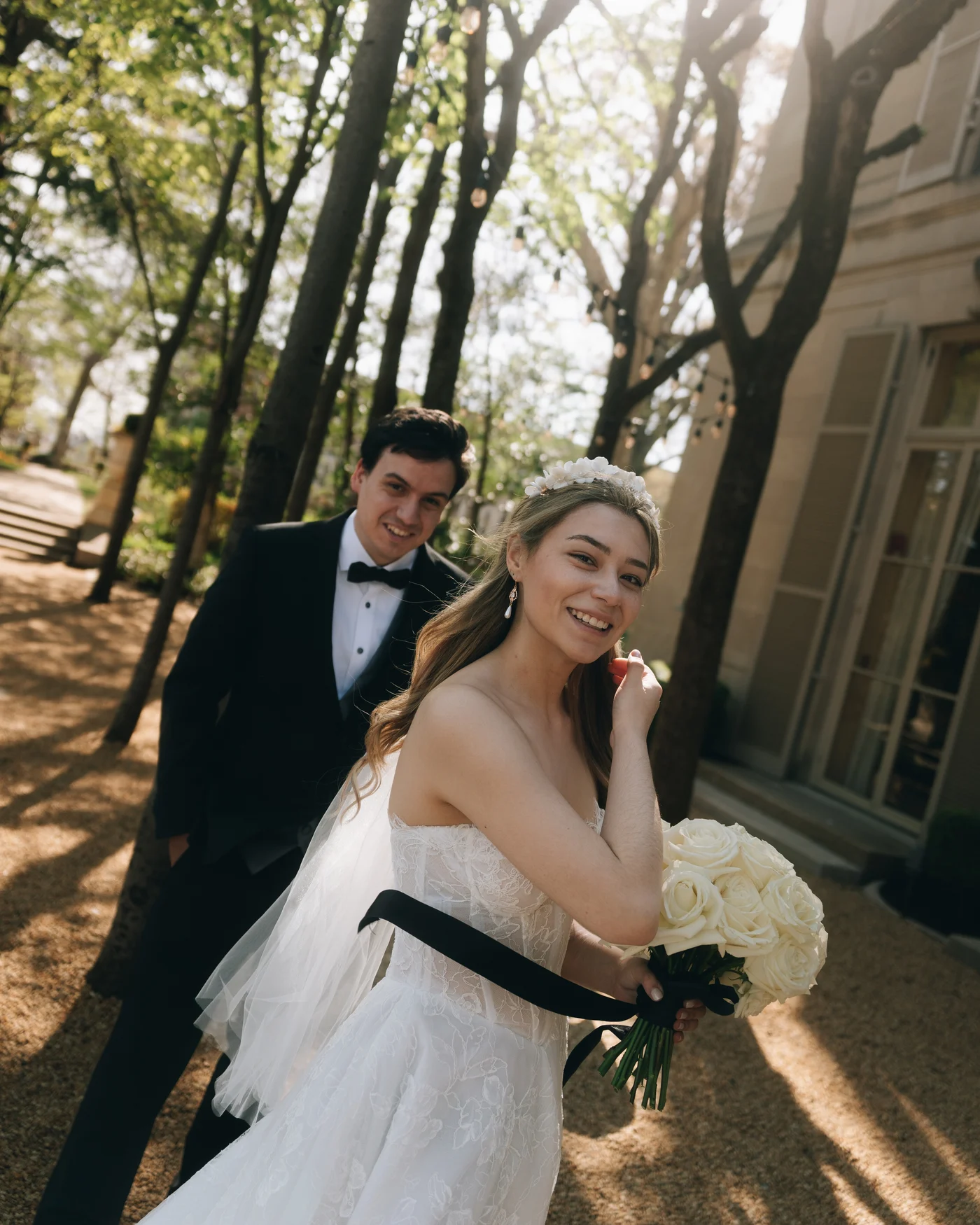 The bride holding her white bouquet, a black sash at her waist