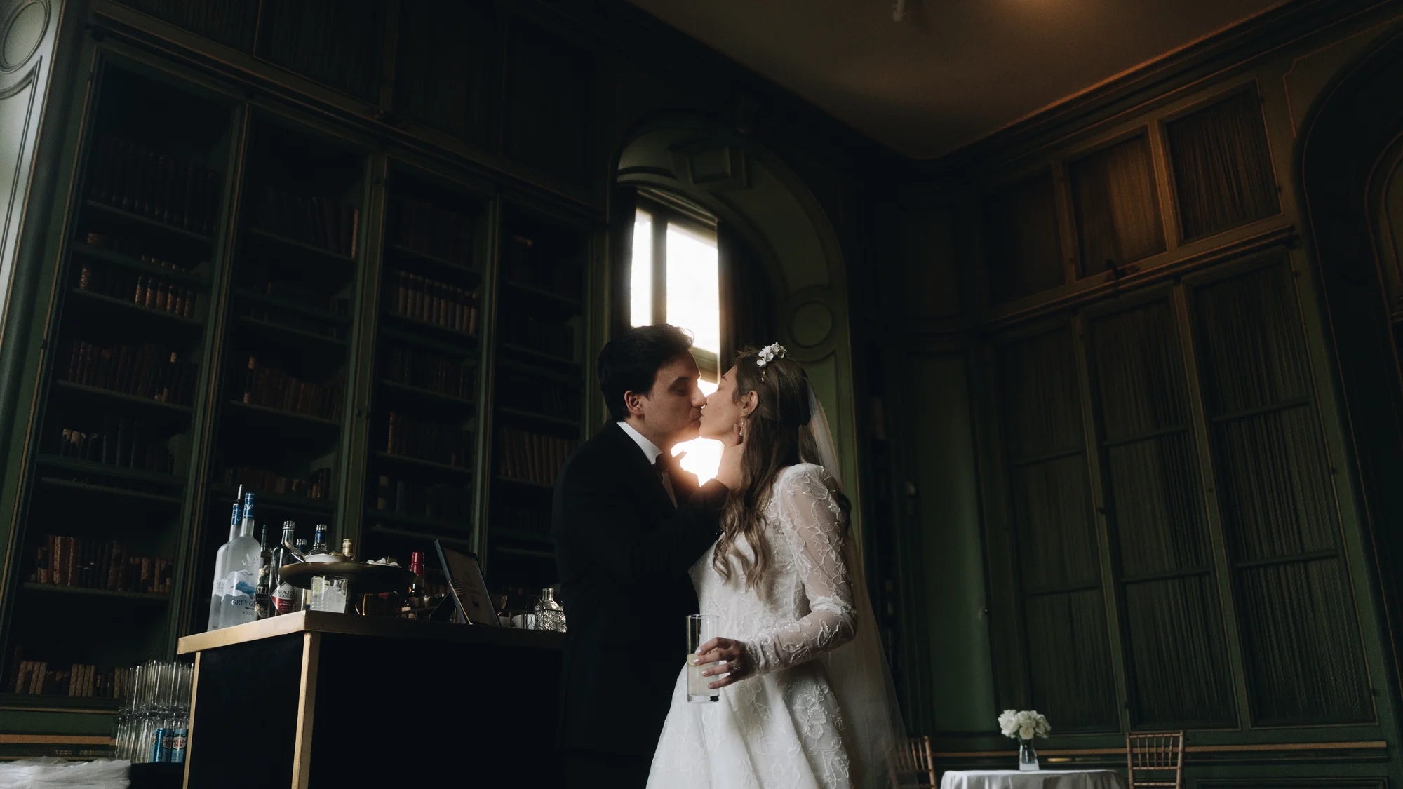 The bride and groom together in the green library, lamplight and dark wood on every side