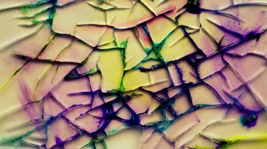 Cracked paint veined with green, purple, and yellow ink, shot close enough to turn abstract