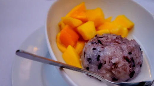 Mango sticky rice on an oval plate, the fruit cut in bright cubes beside the rice