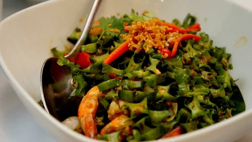 Stir fried winged beans with shrimp, chili, and fried garlic heaped in a white bowl