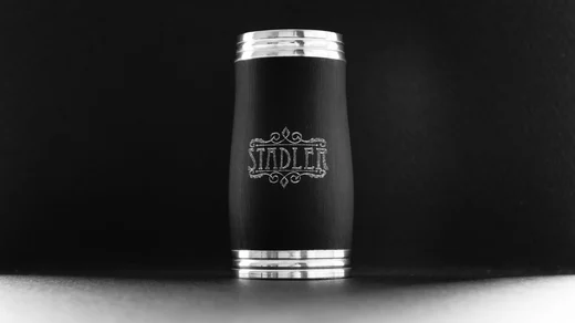A clarinet barrel engraved Stadler, standing upright in a pool of light against black