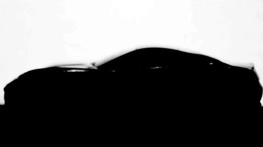 The silhouette of a toy sports car in profile against a blown out white background
