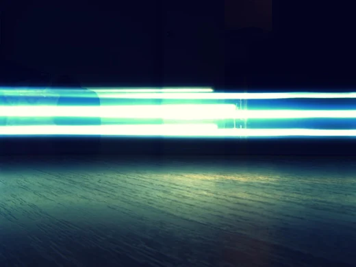 Long streaks of blue fluorescent light smeared across the dark above a wood floor