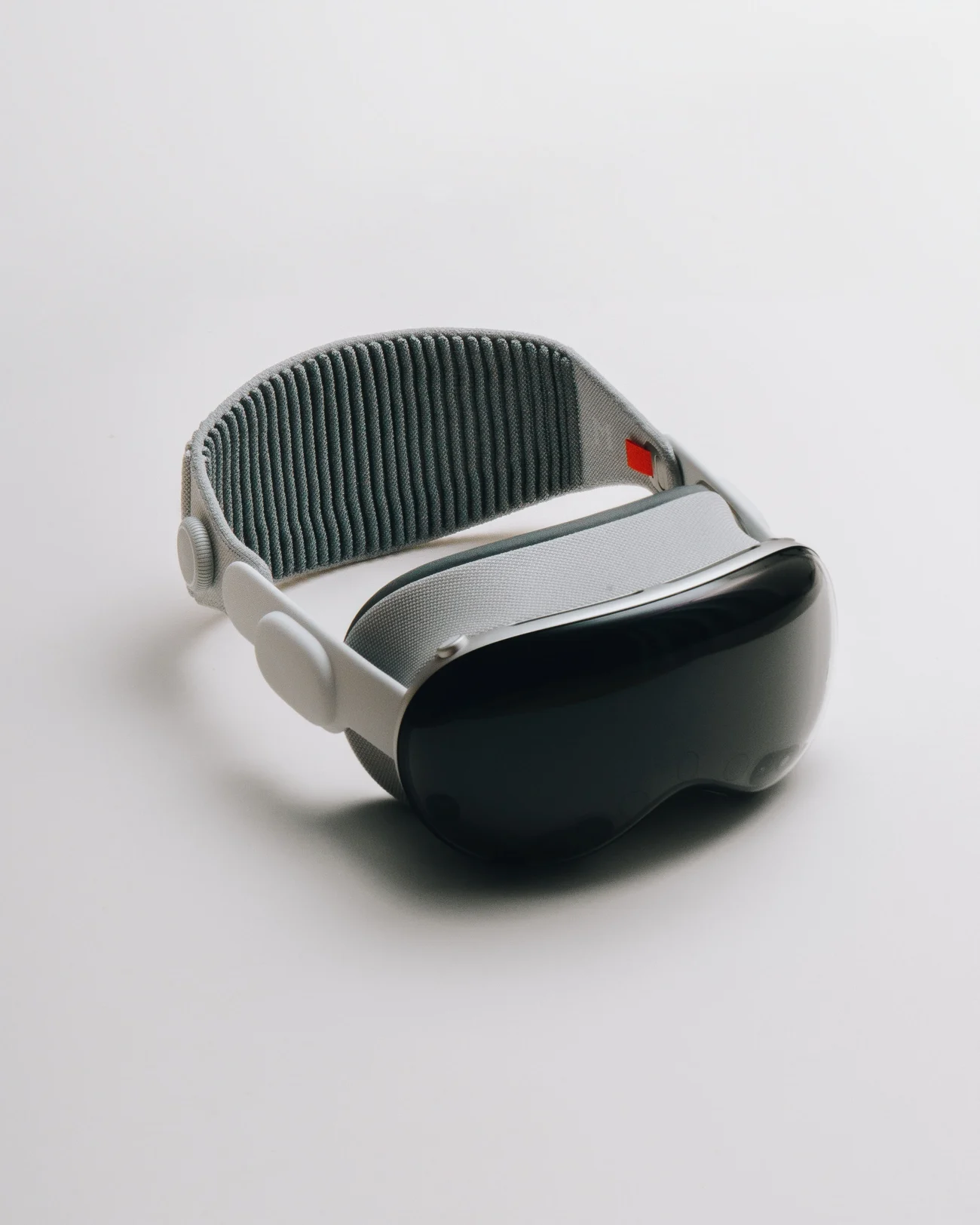 The headset three-quarters on against white, dark curved glass front and brushed silver frame