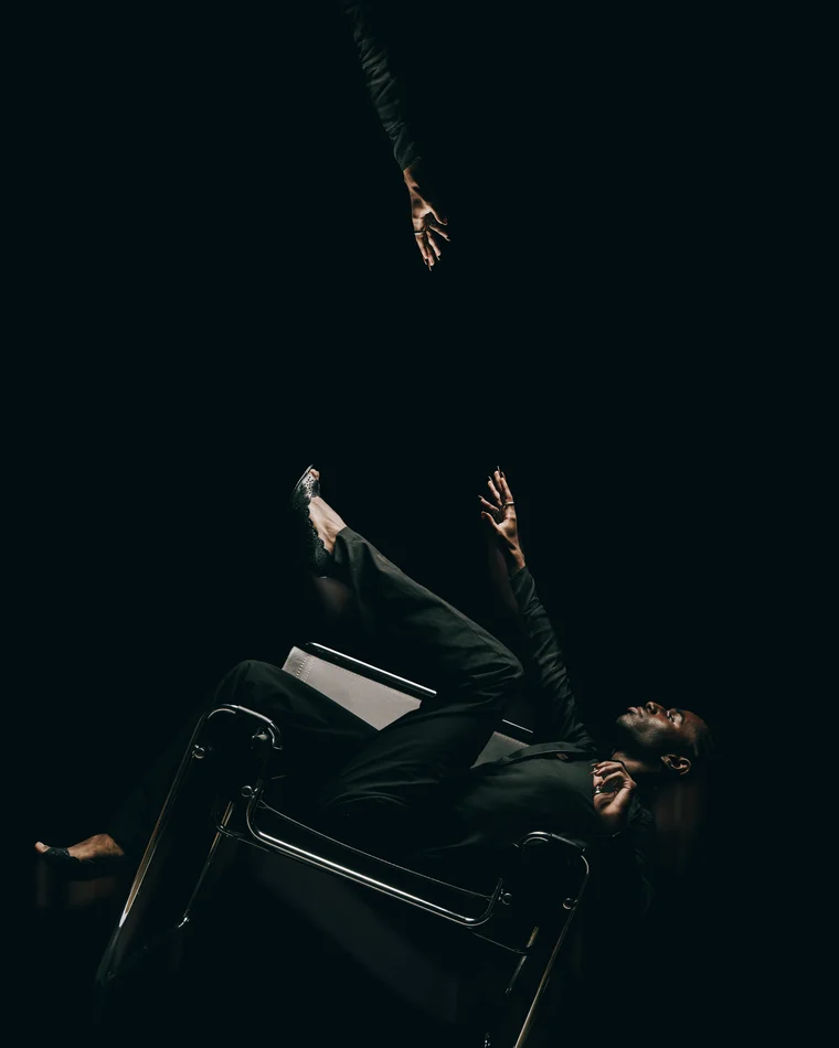 The same figure falling backwards over the chair, one arm flung up, another hand reaching down out of the dark above him