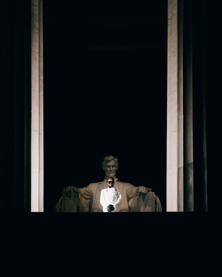 The seated Lincoln lit deep inside his colonnade, a single small figure standing below him in the dark