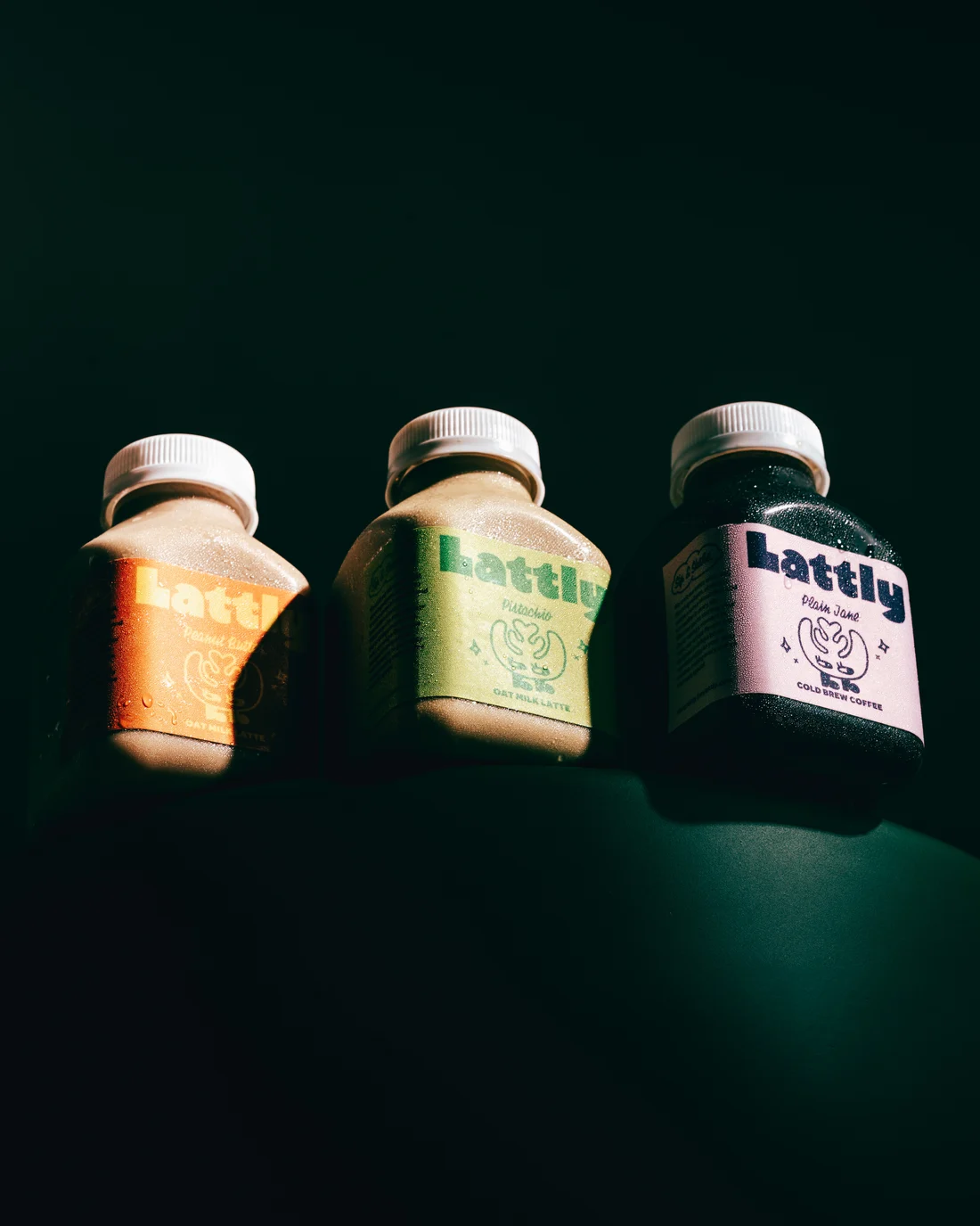 Three Lattly bottles lying in a row on dark green