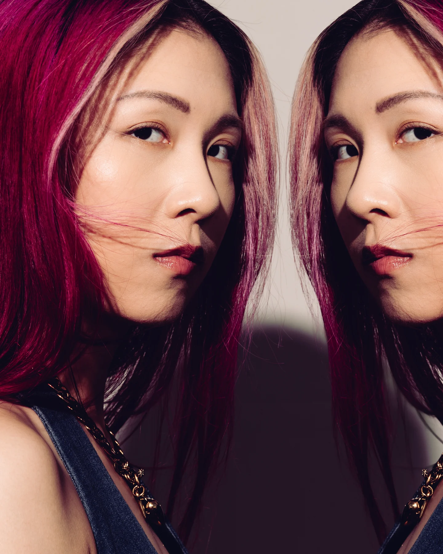 A mirrored double portrait, magenta hair on both sides