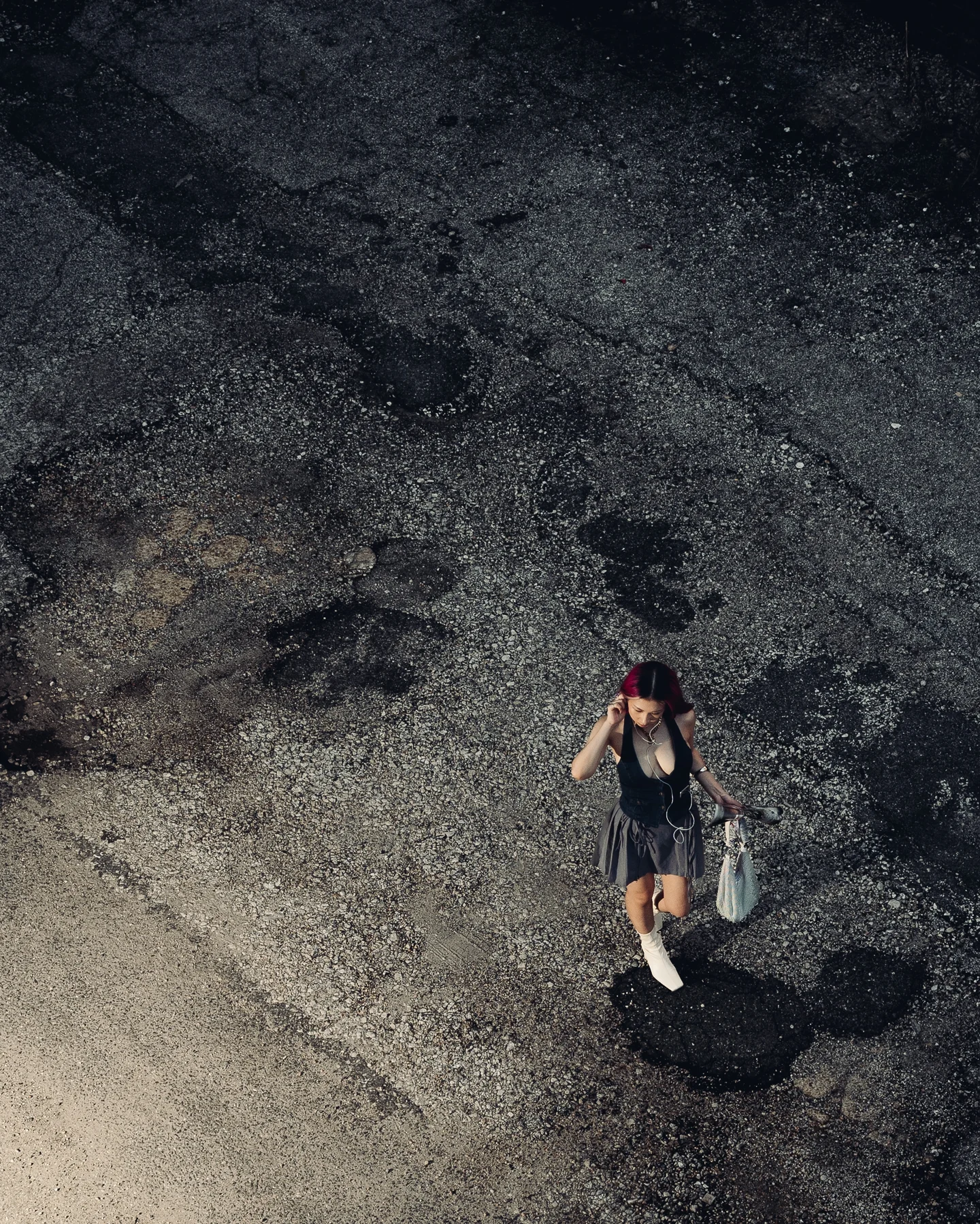 Overhead of a parking lot, one figure crossing the concrete