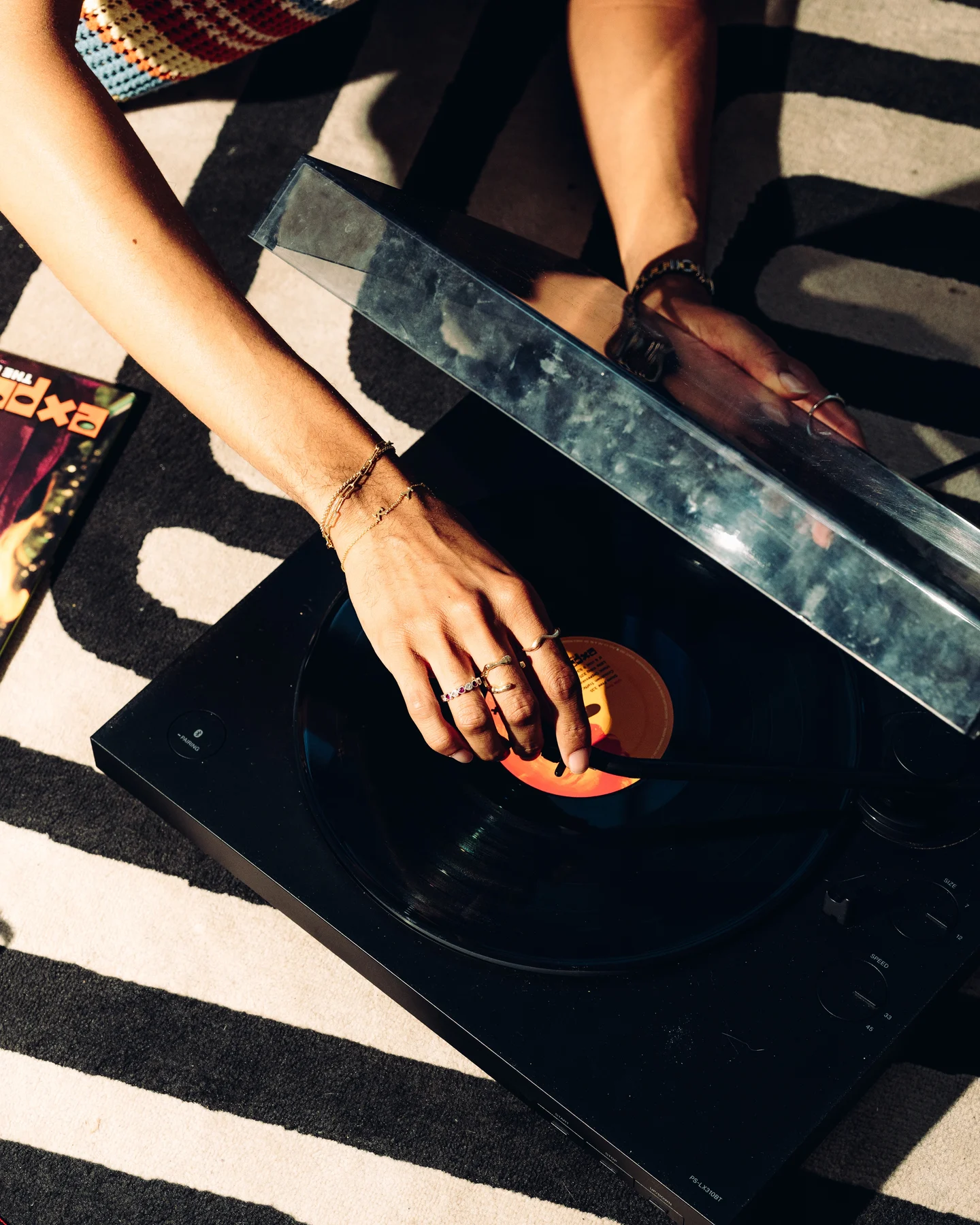 A hand cueing a record on a turntable, a can of Lattly beside it