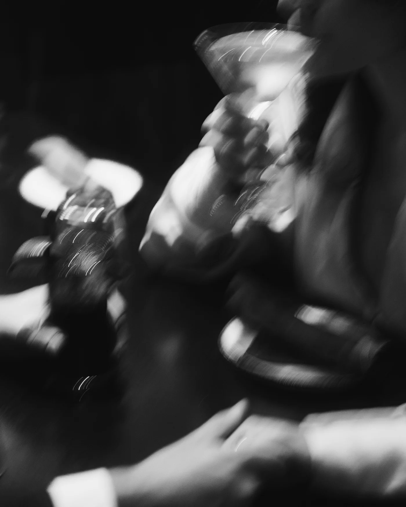 Black and white and deliberately smeared, hands and glasses dissolving into a long exposure