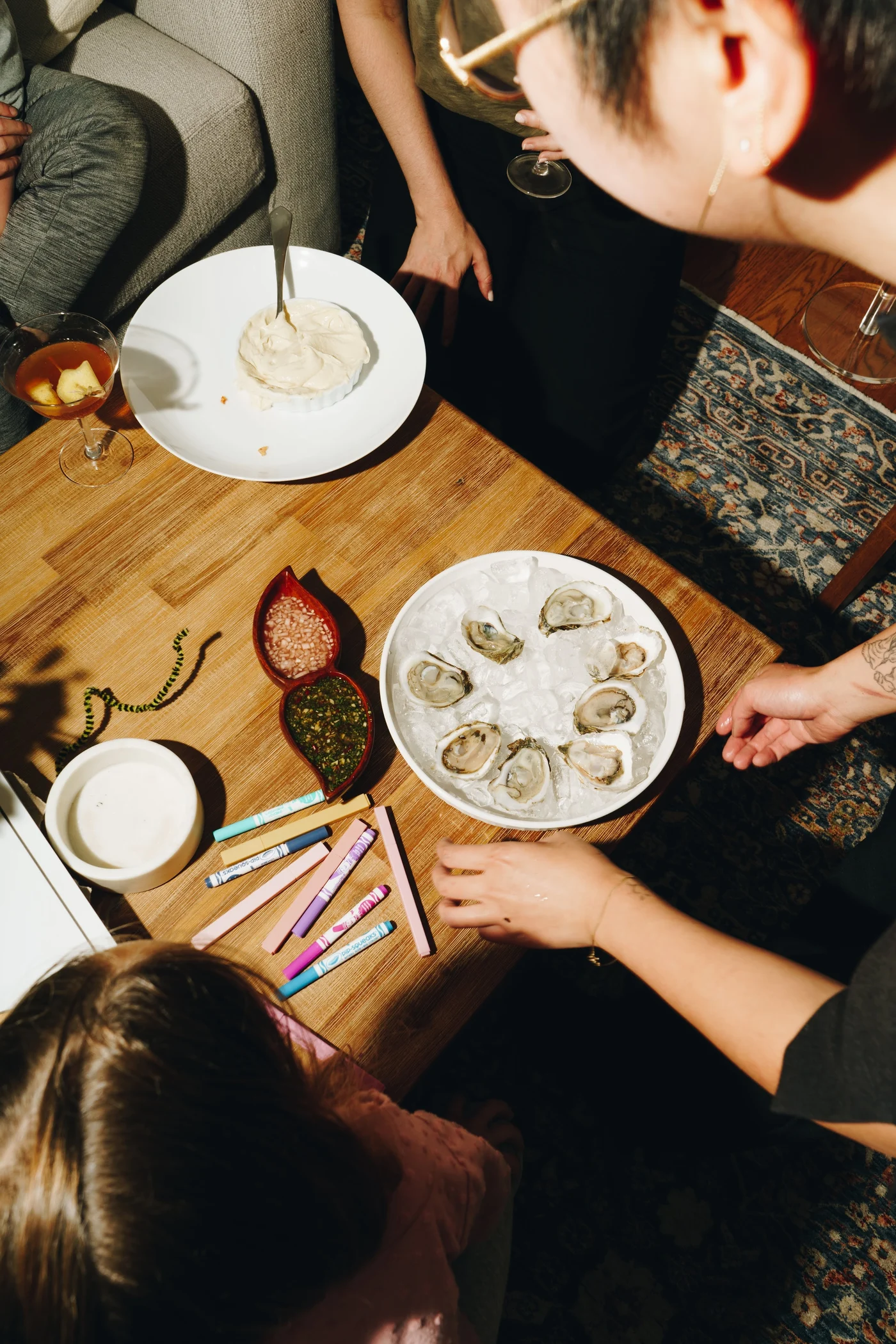 A platter of oysters on ice at the center of the table, crayons scattered within reach