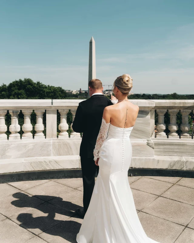 The bride reaches to tap the groom's shoulder for their first look, their shadow stretched across the rooftop pavers