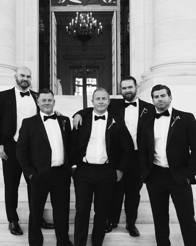 The groom and his groomsmen posed on the front steps, a chandelier burning in the doorway behind