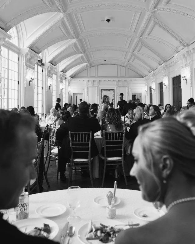 Black and white view across the dinner tables, the vaulted plaster ceiling arching over the full room