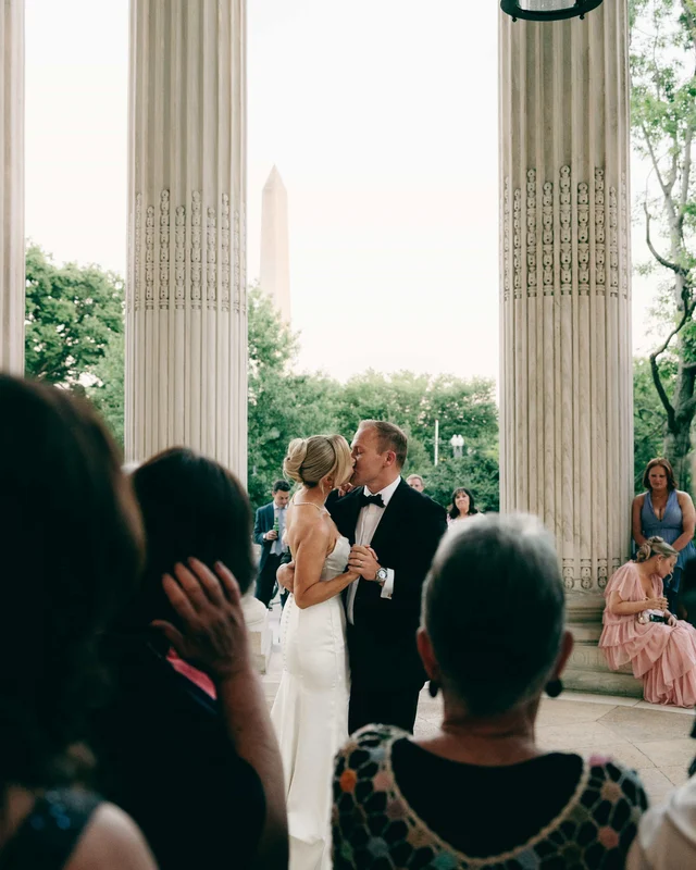 The first dance beneath the colonnade at dusk, the monument silhouetted between the columns