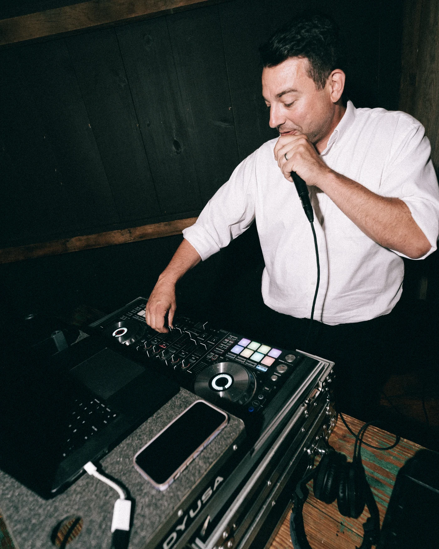 The DJ at the decks in the dark barn