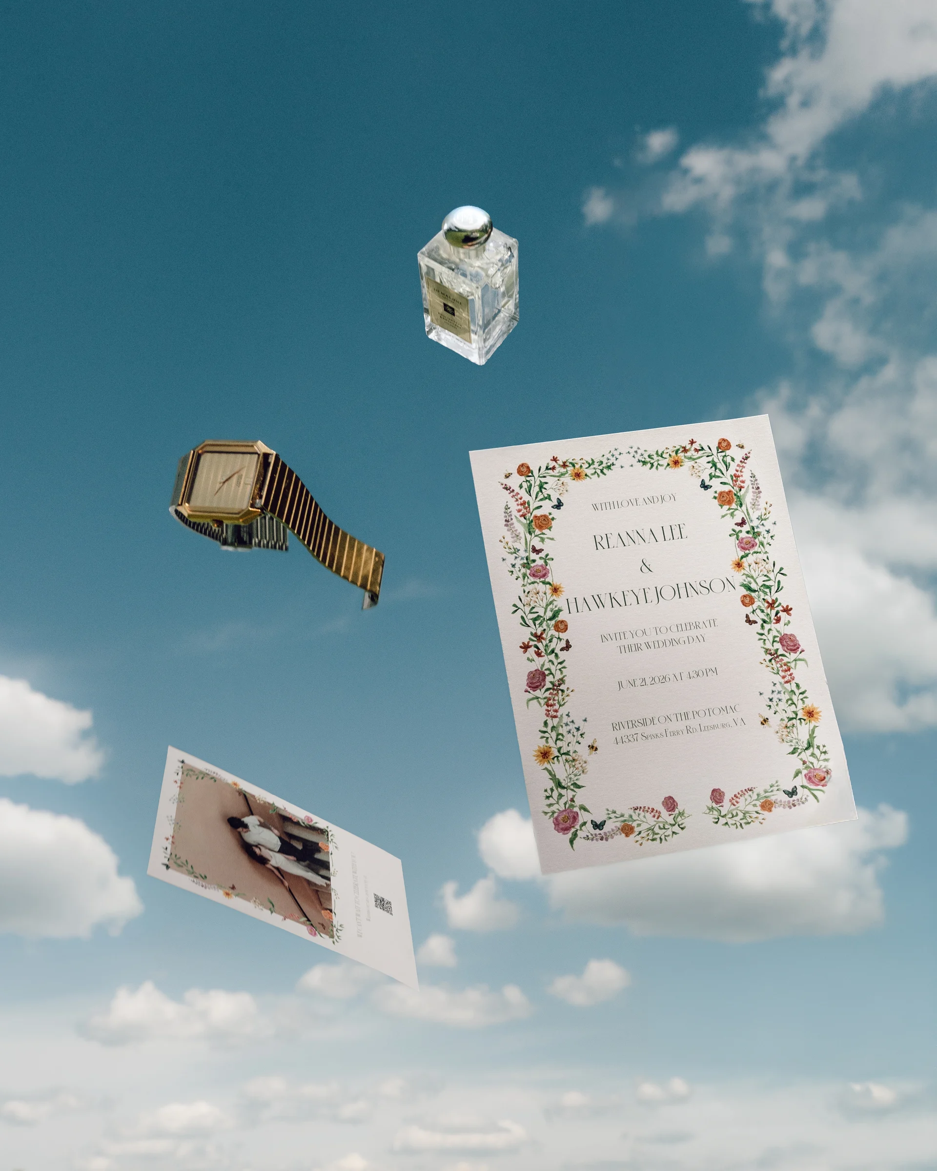 A wedding invitation suite thrown up against a blue sky, the invitation, a photograph, a watch and a bottle of scent all caught mid air among the clouds