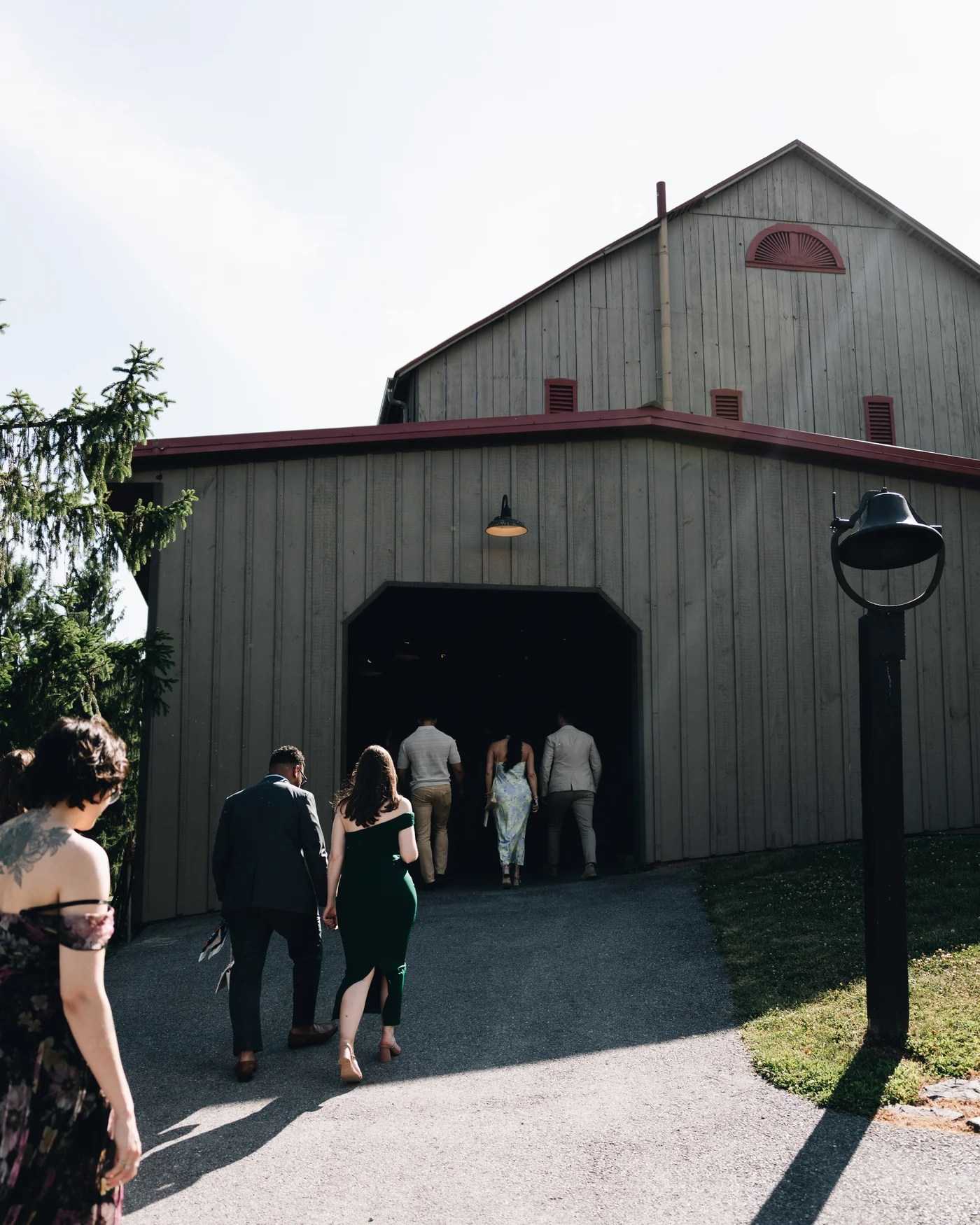 Guests walking into the lower side opening of the barn in the last of the daylight