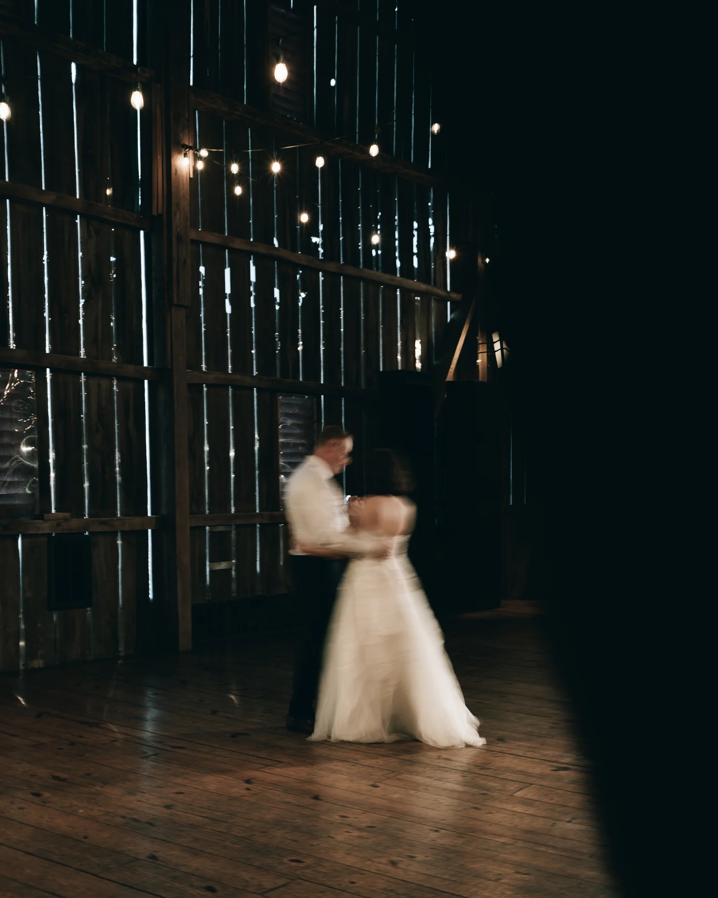 The couple dancing, blurred, under the string lights