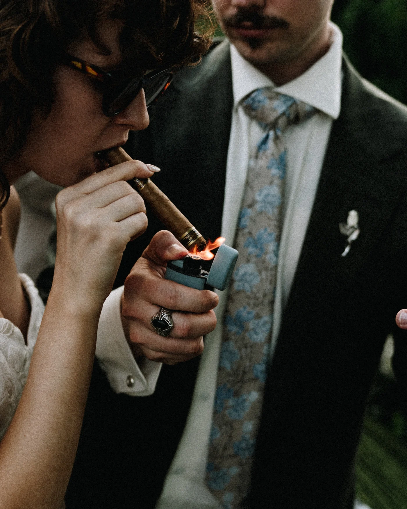 The groom lighting a cigar outside with his friends