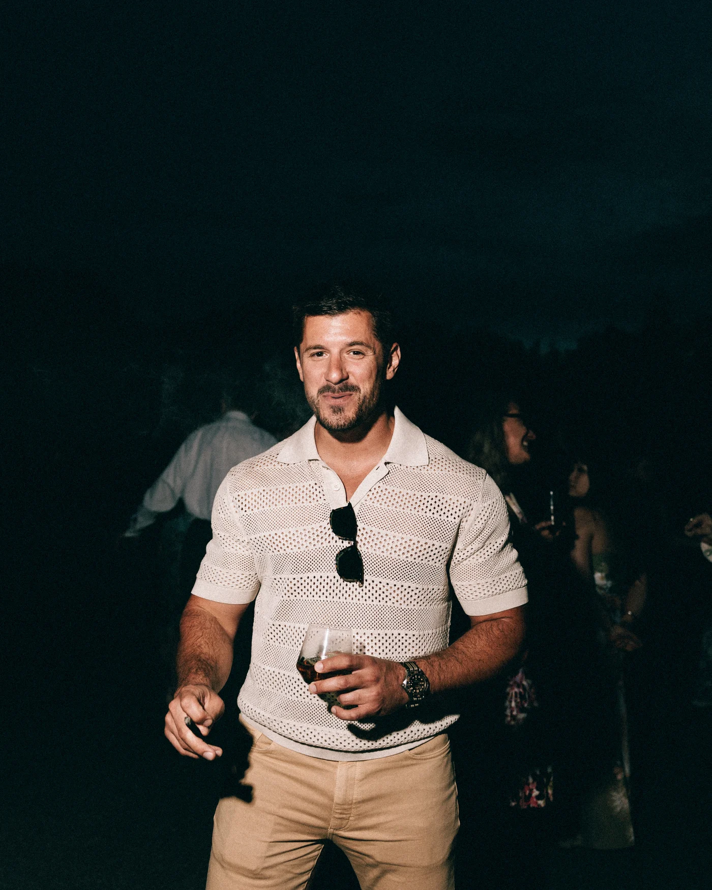 A guest holding a drink on the lawn after dark