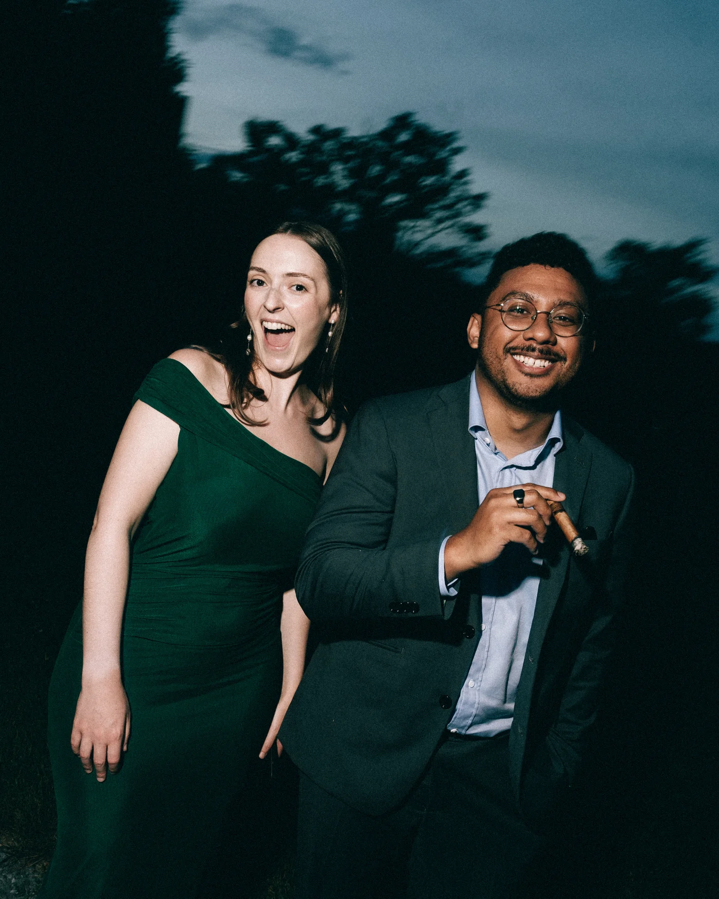 Guests laughing together outside, one of them holding a cigar