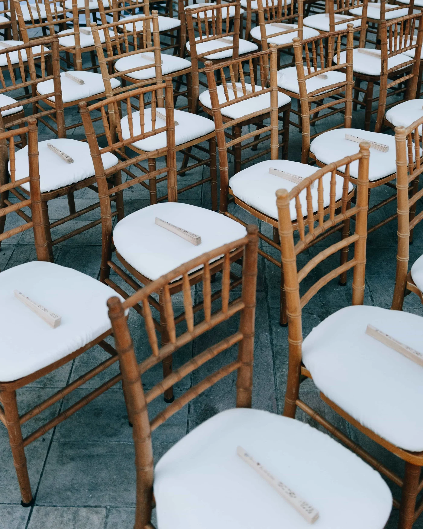 Rows of bamboo chairs waiting for the ceremony, a folded wooden fan laid on every white cushion