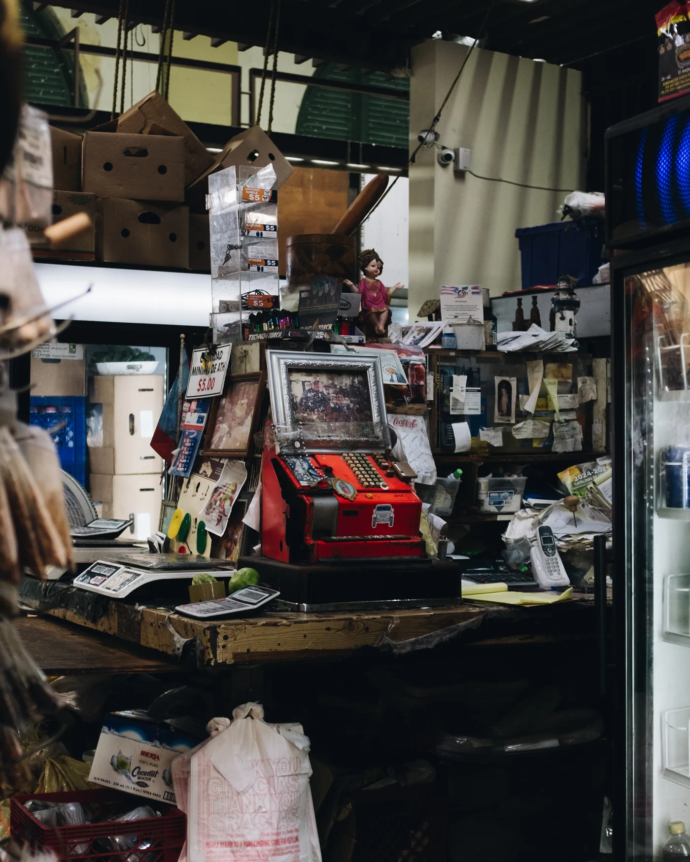 A scarlet antique cash register buried in the beautiful clutter of a shop counter