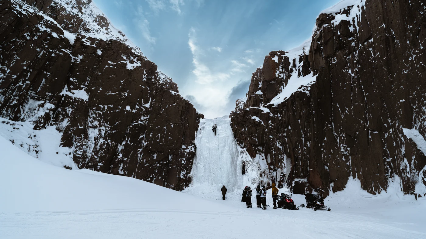 A frozen waterfall, climbers on it, watched over a hot lunch.