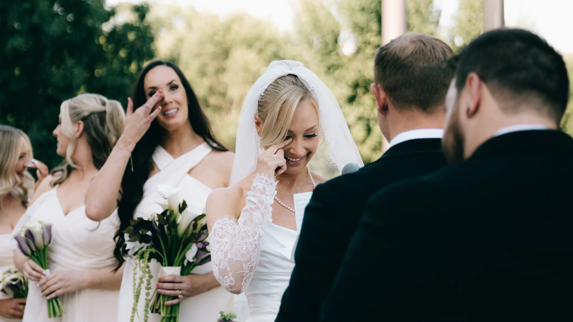 The bride wiping away a tear and laughing during the ceremony, a bridesmaid behind her doing the same